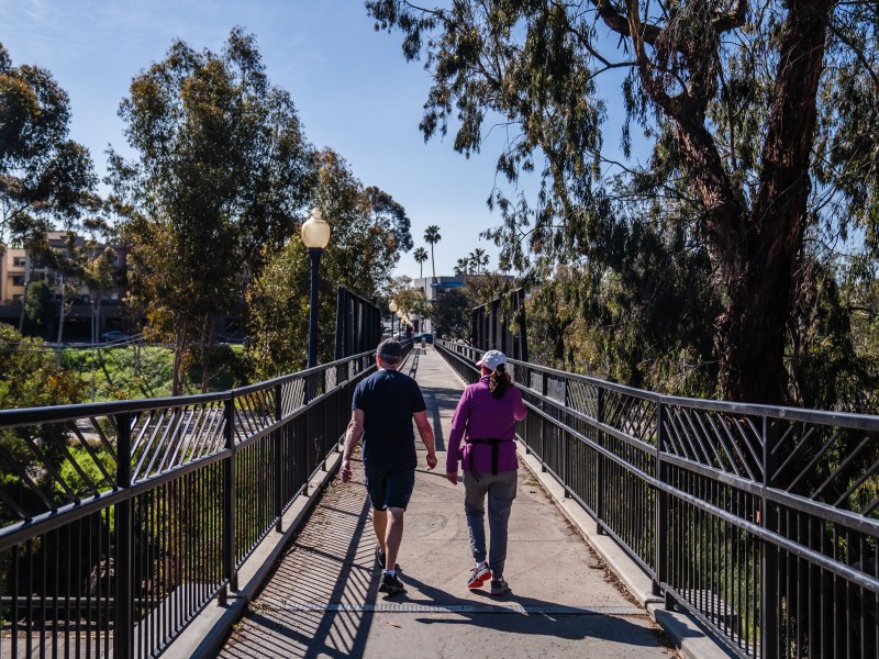People walk on the Vermont Street pedestrian bridge in University Heights on March 3, 2023.